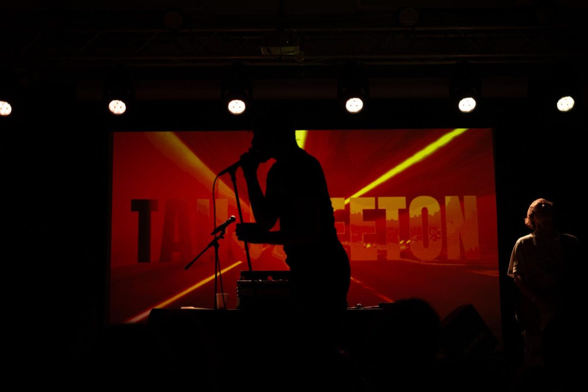 Keeton stands silhouetted against his projected backdrop. The backdrop changed colors throughout the performance.