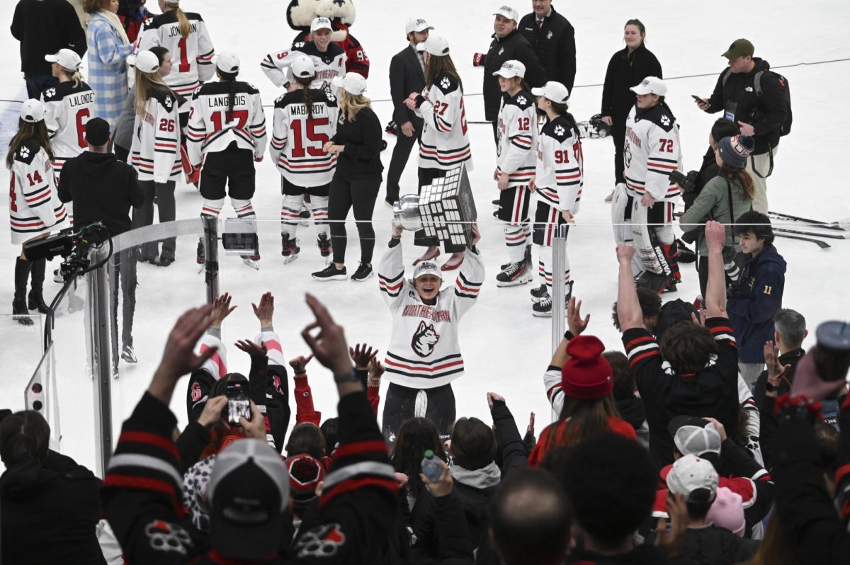 Ella Blackmore holds the Beanpot trophy over her head. The Huskies shutout Boston University 4-0 Jan. 21.