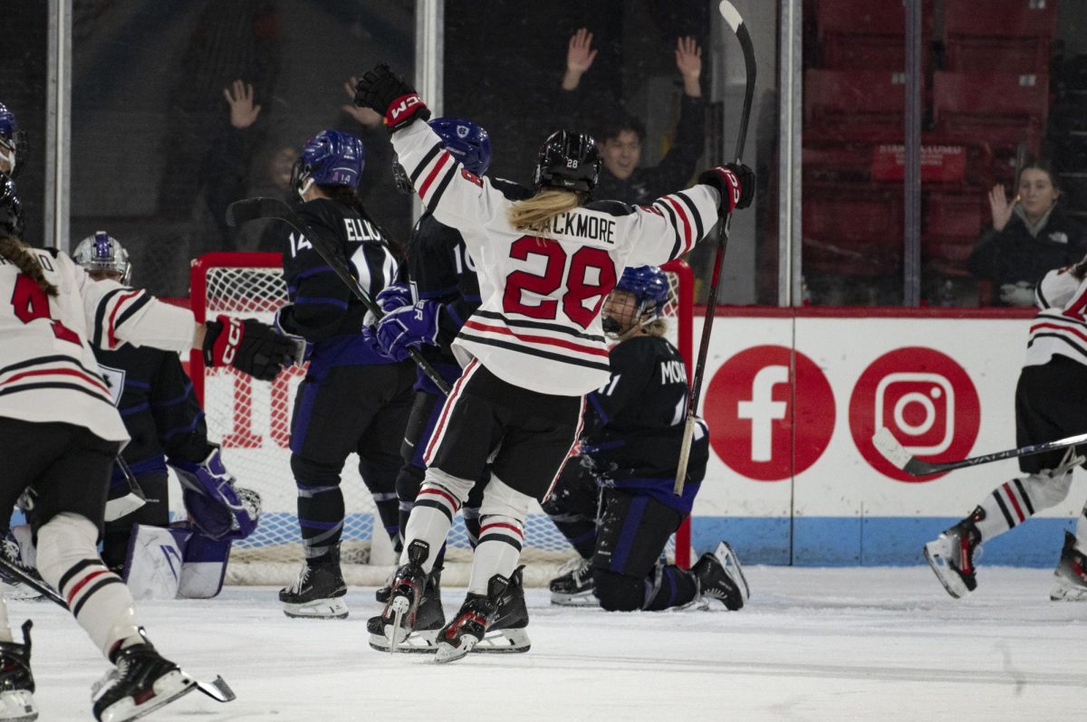 Sophomore forward Ella Blackmore lifts her hands in celebration Jan. 4. Northeastern came out strong in the first period against the warriors, the team shooting off 19 shots and dominating puck time.
