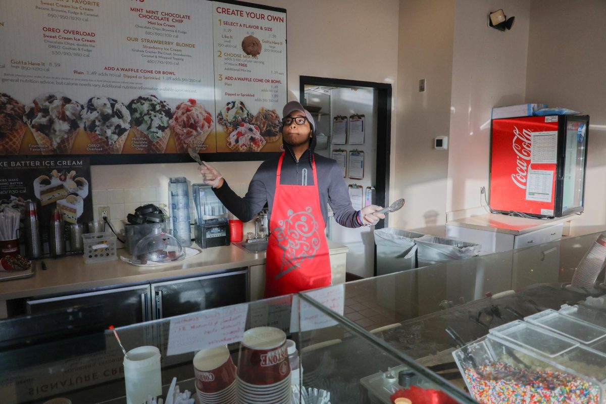 A Cold Stone Creamery employee prepares an order of ice cream. The employee threw and caught scoops of ice cream with two spatulas.