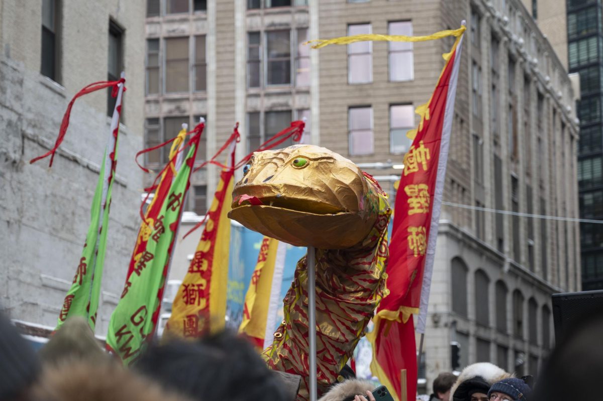 A parade participant holds up a golden snake figure. Large, colorful triangular flags were also a common sight.