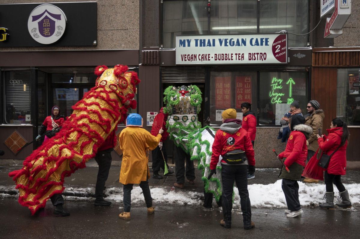 Two dragons dance in front of My Thai Vegan Cafe. After each storefront visit, performers swapped roles of who danced as the lion and who supervised.