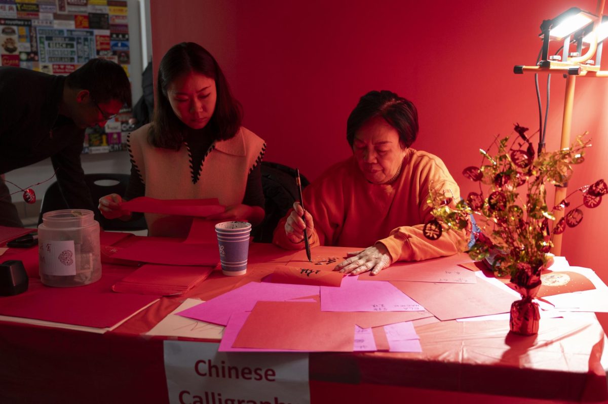 A woman writes Chinese characters using a traditional calligraphy brush and ink. Visitors were given a red paper with the transliteration of their English name in Chinese.