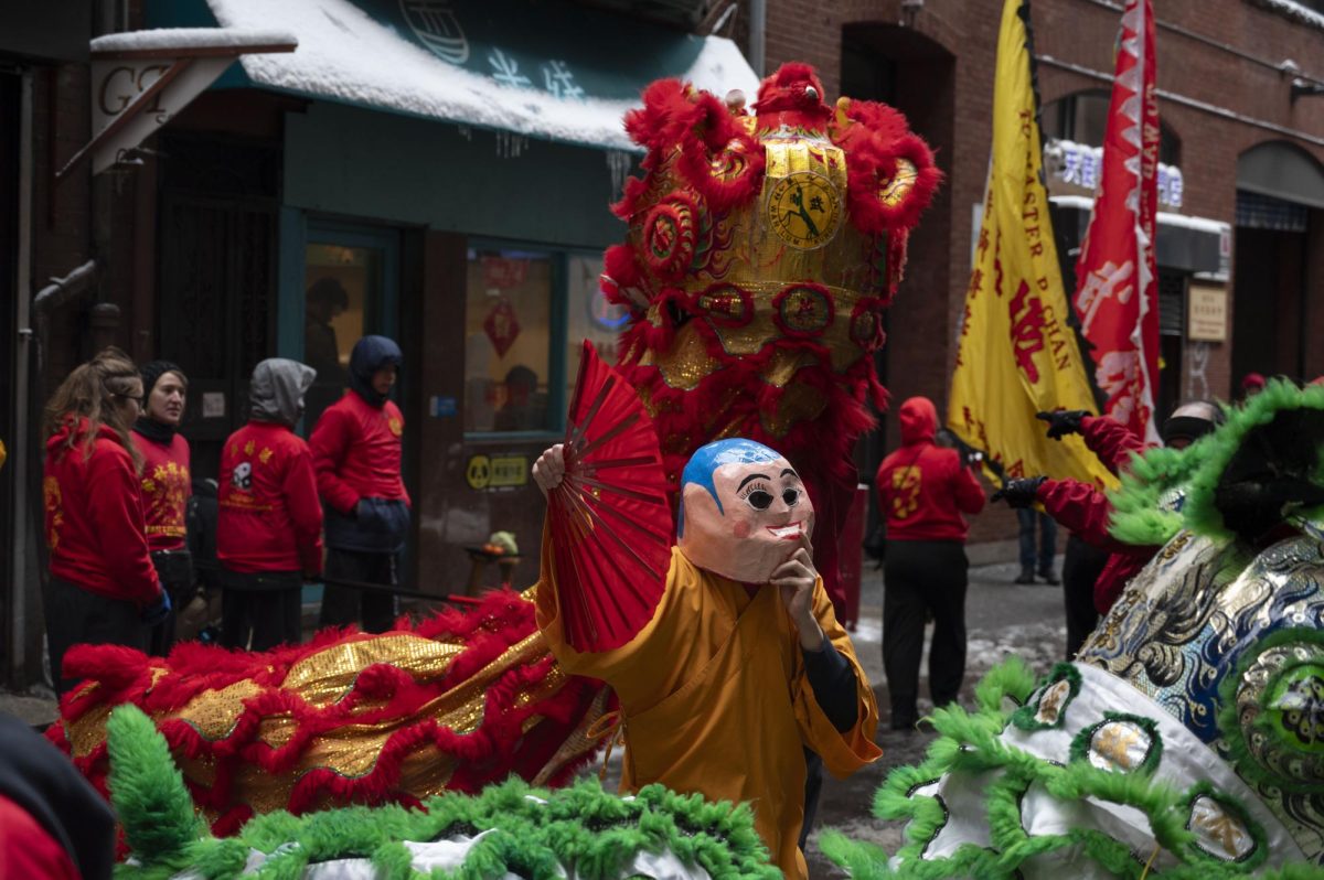 A performer dressed as the Buddha waves a red fan. The Buddha danced with the lions, providing extra entertainment for onlookers.