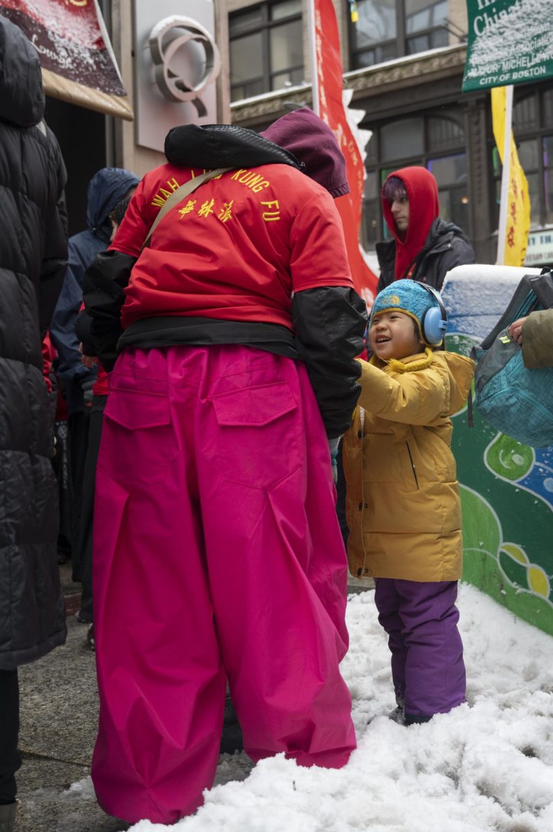 A child hands a Wah Lum Kung Fu member a note. Red envelopes were exchanged between performers and audience members throughout the parade.