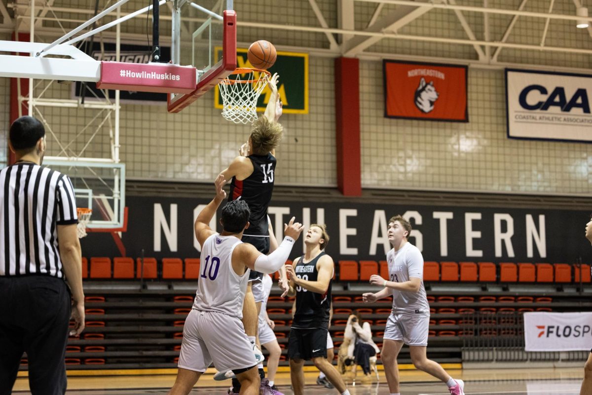 A men's club basketball player goes in for a layup. The team split with Tufts University in its conference-opening weekend series Dec. 7, winning the first matchup 68-56 and losing the second by a slim margin, 77-75.