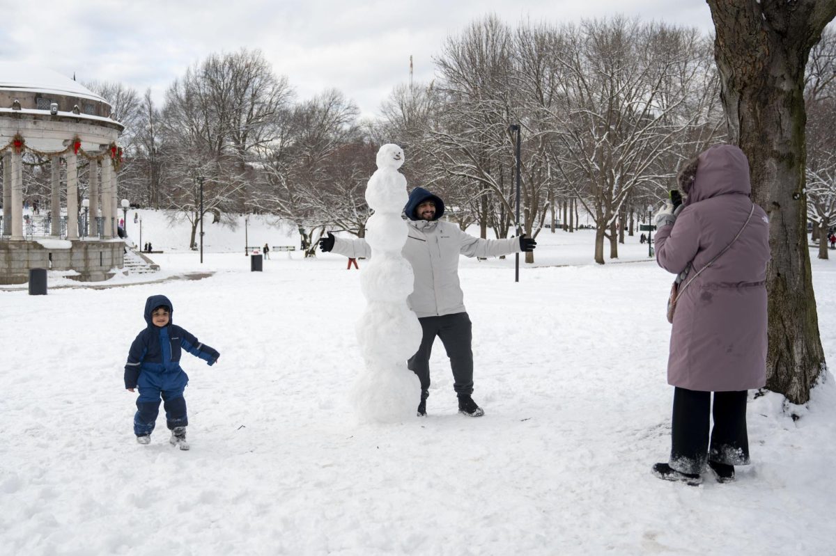 A man and his child pose with a six-part snowman in Boston Common. Hundreds of overlapping snowy footprints covered the Common.