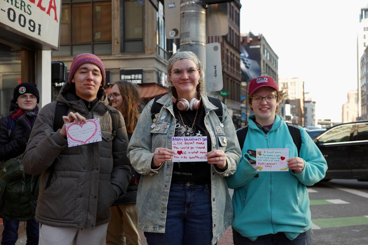 Students from Emerson College stand with Valentine’s Day cards. They unexpectedly received the cards while waiting for the crosswalk.