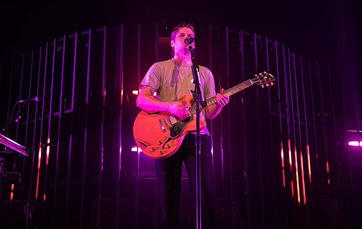 Mark Foster sings to a House of Blues crowd while playing bass. The intricate background lights flashed colorful gradients and lyrics while he sang.