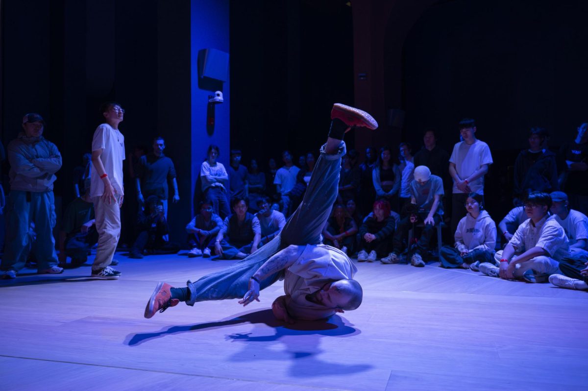 A b-boy performs a windmill. He propelled himself into a rotational movement without the use of his hands or feet, balancing on just his back, head and elbows.