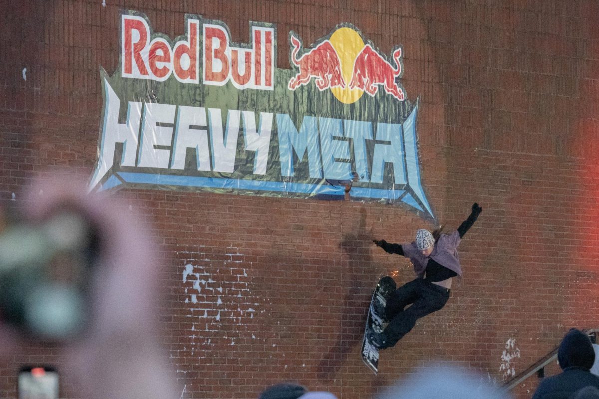 Sparks fly from Maggie Leon's board as she performs a wallride next to the Heavy Metal logo. Some riders would launch high enough to touch and cut the Red Bull decal with their snowboard edge.