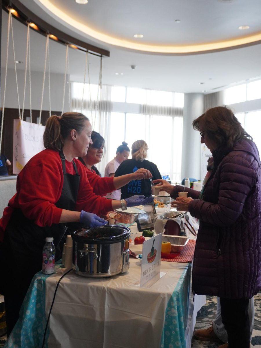 A vendor hands a cup of chili to an attendee. The competition charged $10 for 10 cups of competing chili.