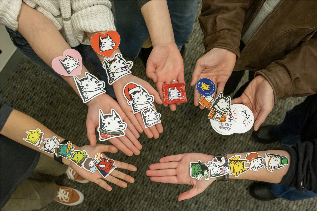 Hoosky team members show off two years worth of sticker designs along their arms and hands Feb. 18. Sticker designs ranged from a pixelated husky to character-based huskies such as Pikachu or Spider-Man.