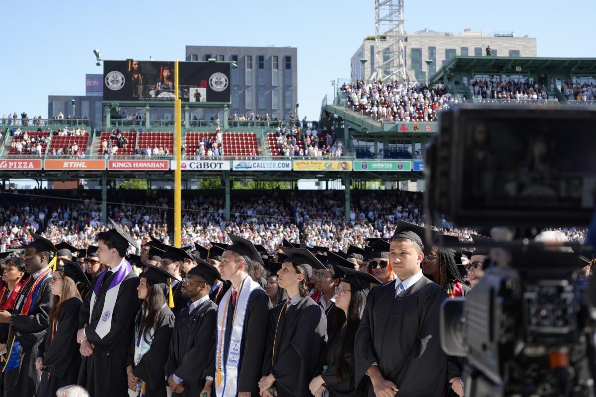 Graduating students stand as a camera films the 2025 commencement in Fenway Park May 11. Each individual college, such as D'Amore-McKim School of Business and CAMD, hosted a graduation ceremony for its students the week before commencement.