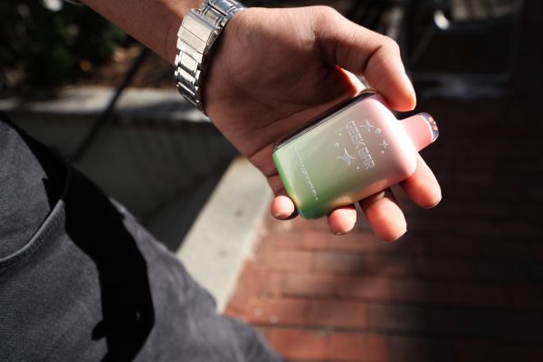 A person holding a sour strawberry flavored Geek Bar vape. Vaping linked to serious side effects such as lung cancer and seizures.