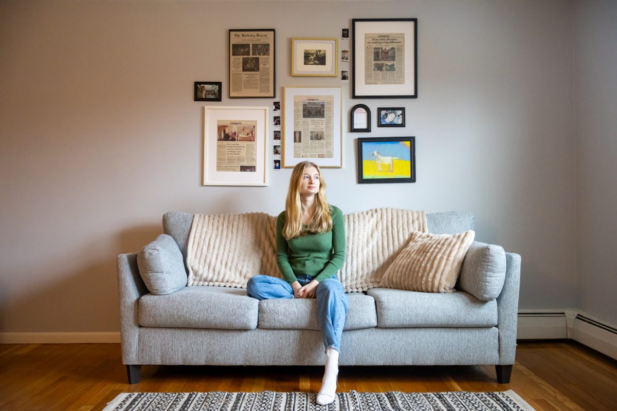 Adri Pray sits on the couch in her apartment in Westborough, Mass. Jan. 17. Pray framed several of her articles from The Berkeley Beacon and The Boston Globe. 