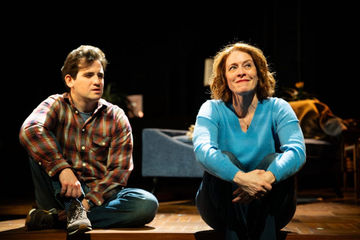 Joshua (Will Conard, right) and Ellen (Eva Kaminsky) sit on the stage under a spotlight. “We Had a World” debuted Feb 12. Photo courtesy Annielly Camargo, The Huntington Theatre.