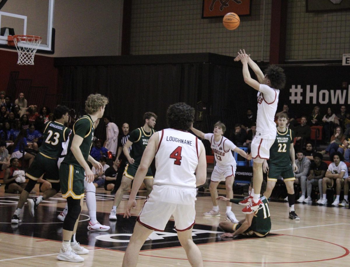 Freshman guard Xavier Abreu (right) jumps for a shot Feb. 12. Abreu ended the season as the Huskies' top scorer with 364 points.