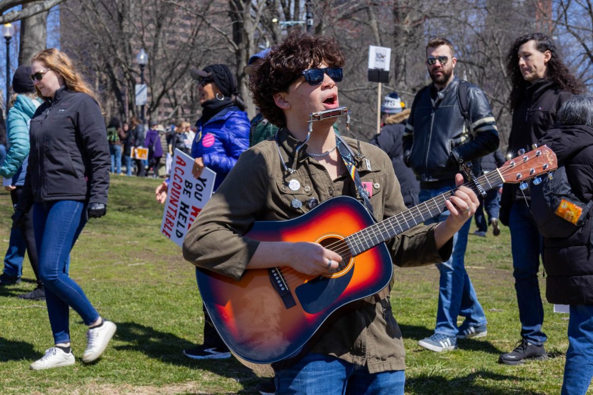 A musician plays the guitar and sings to the crowd of protesters. The Boston Common echoed with music and chants.