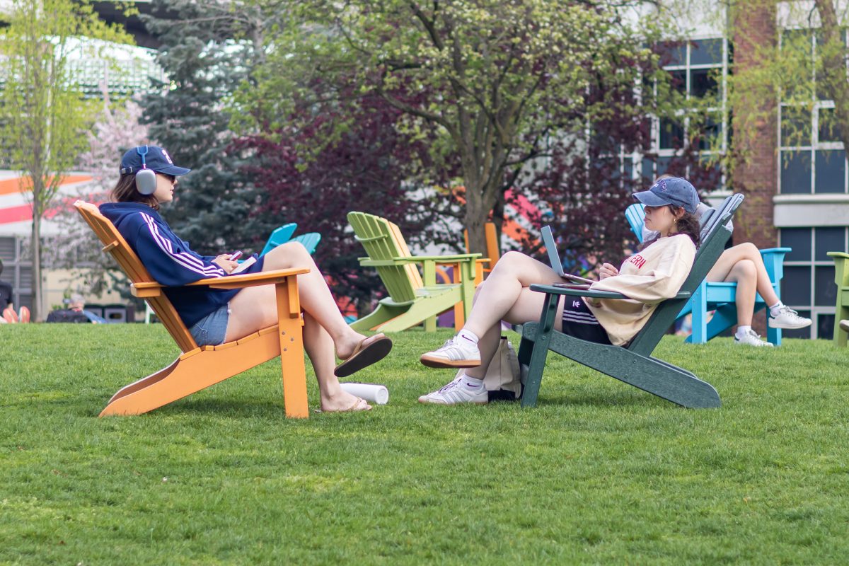 Two students face each other on Centennial Common while reclining in Adirondack chairs April 29, 2025. Northeastern's shorter semester schedule, co-op opportunities and study aboard programs often left students feeling isolated.