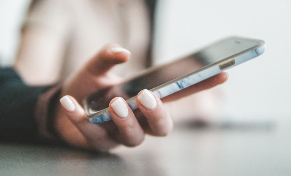 A person holds a smartphone. Instant communication and messaging was first adopted in 1996 by ICQ. Photo courtesy Jae Park, Unsplash.