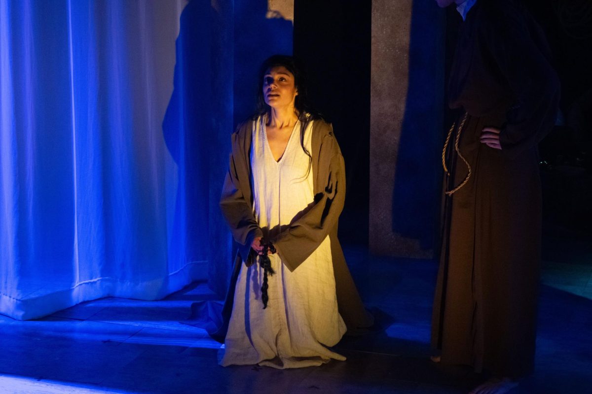 Clare (Hannah Arahim) kneels on the ground during a scene. "Poor Clare" illustrated the life of St. Clare of Assisi and her canonization as a saint.
