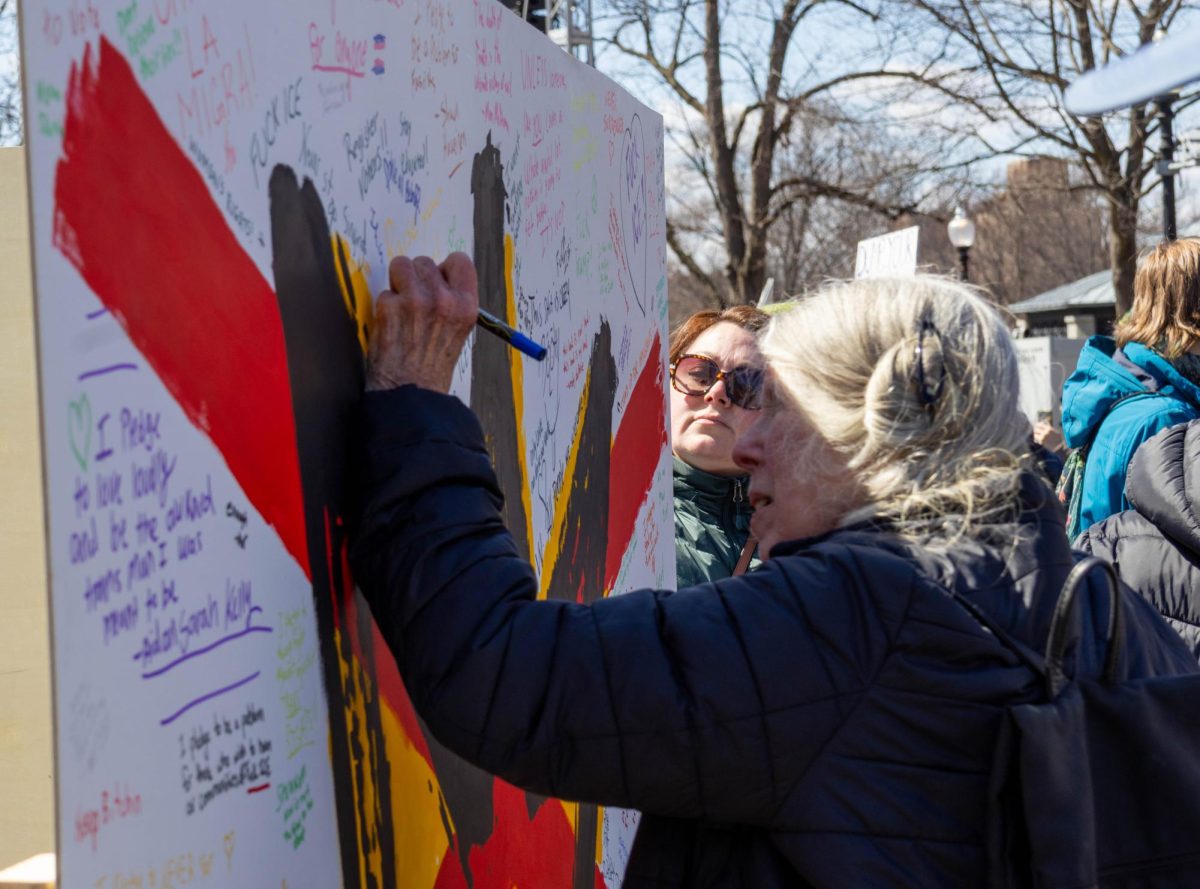 A demonstrator signs a poster while an onlooker waits their turn during the “No Kings” protest at Boston Common March 28. Read more here.