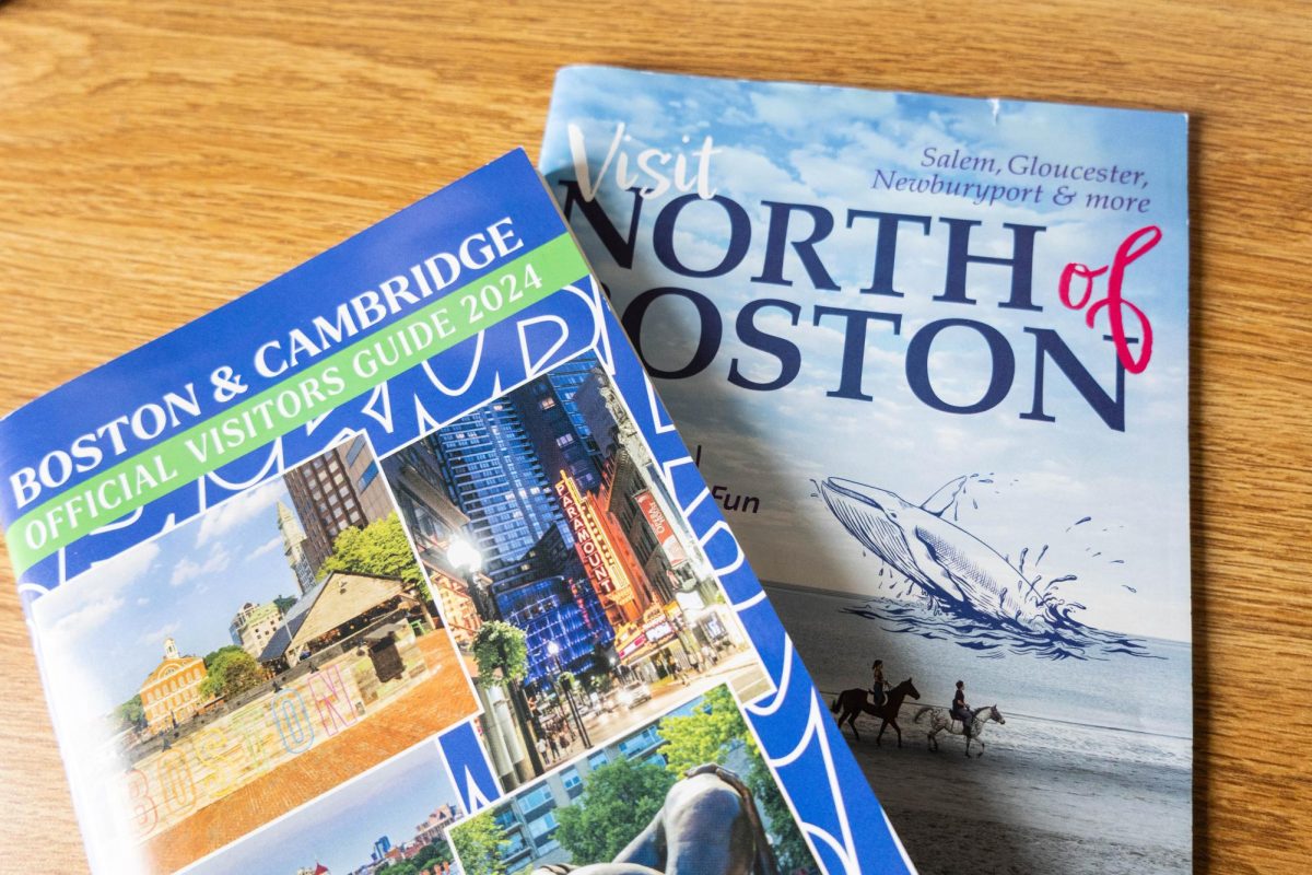 Guidebooks to visit Boston sit on a wooden desk. Boston ranked first nationally for their public school system and MBTA's functional transportation system.