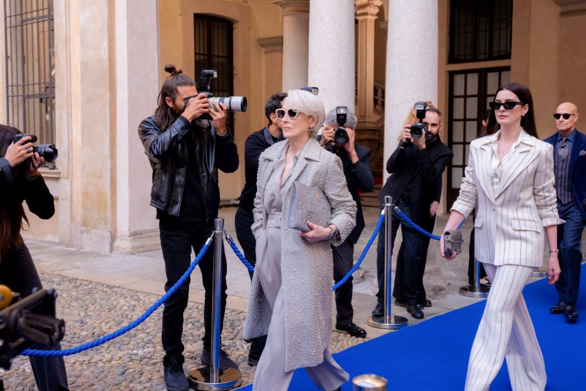 Miranda Priestly (Meryl Streep, left) and Andy Sachs (Anne Hathaway) walk down a carpet surrounded by paparazzi photographers. "The Devil Wears Prada" was released in 2006, its sequel debuting 20 years later. Photo courtesy Macall Polay, 20th Century Studios.